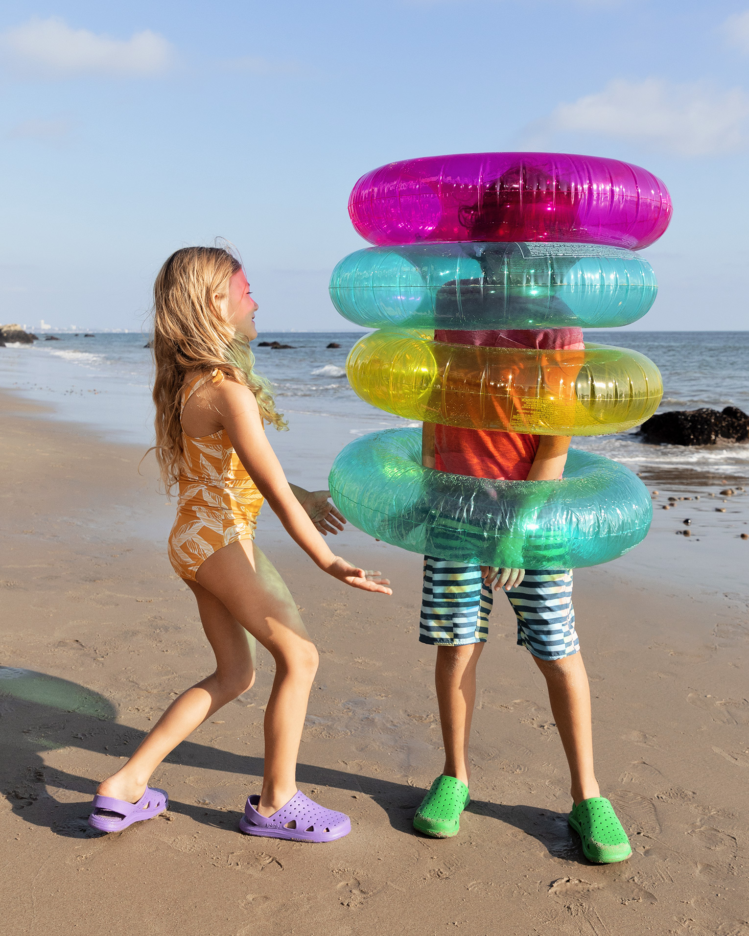 Sun-soaked beach adventure: Two kids play joyfully in Totes advertising image by Kimberly Genevieve