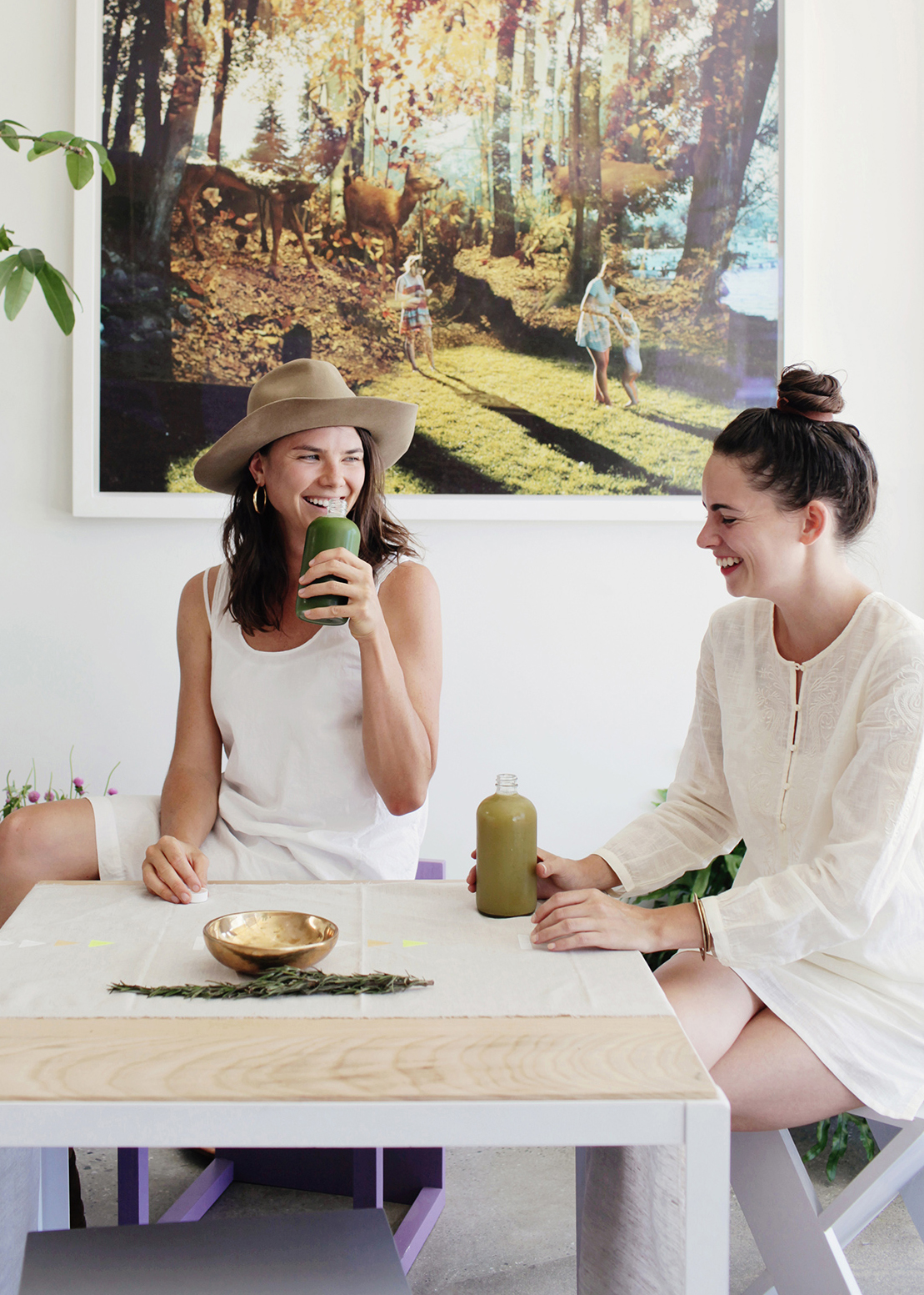 Joyful advertising moment by Kimberly Genevieve: Two women share laughter while enjoying healthy juices